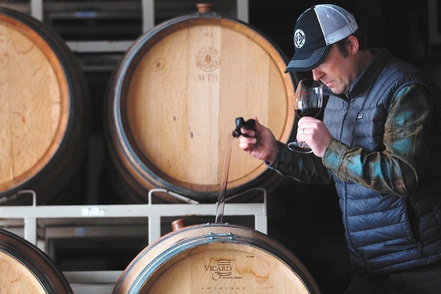 A wine maker tasting his wine from the barrel
